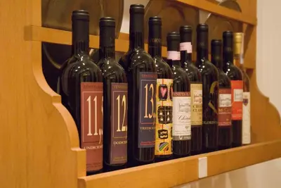 a bunch of wine bottles on a wooden shelf at Hotel Locanda Cairoli in Rome