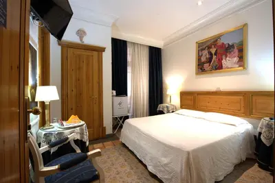a bedroom with a bed and a table and a chair at Hotel Locanda Cairoli in Rome