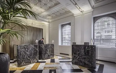a man standing at a podium in a large room with black marble at InterContinental Rome Ambasciatori Palace by IHG in Rome