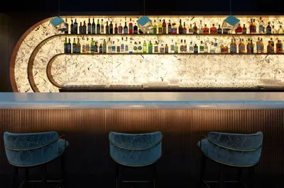 a bar with blue stools and bottles of alcohol at InterContinental Rome Ambasciatori Palace by IHG in Rome