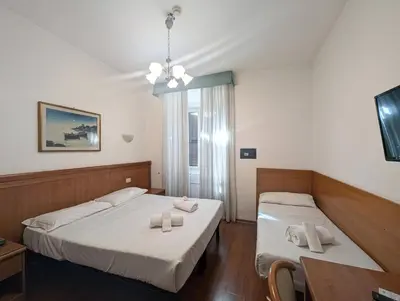 a bedroom with two beds and a table and a window at Hotel Ventura in Rome