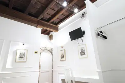 a room with white walls and a ceiling with wooden beams at Domus Ester in Rome