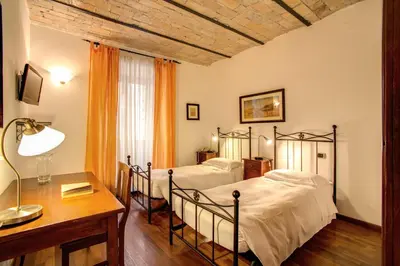 a bedroom with two beds and a desk with a lamp at Residenza Domizia in Rome