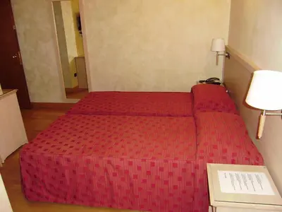 a red bed in a small room with a lamp at Dipendenza Hotel Galileo in Rome