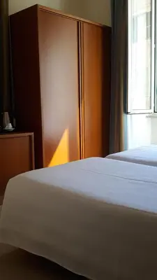 a hotel room with two beds and a window at Crosti Hotel in Rome