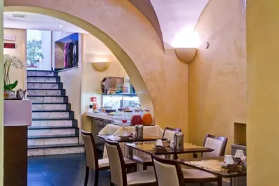 a restaurant with tables and chairs and a staircase at Crosti Hotel in Rome