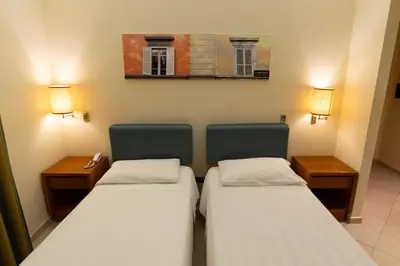 a small room with two beds and two desks at Crosti Hotel in Rome