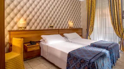 a hotel room with a bed and a chair at Hotel Assisi in Rome