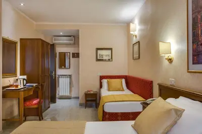a hotel room with two beds and a desk at Hotel Silla in Rome