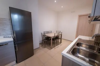 a kitchen with a black refrigerator and a table with chairs at Casa Rosa Beige e Blu in Rome