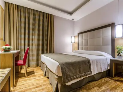 a hotel room with a bed and a red chair at Hotel Giolli Nazionale in Rome