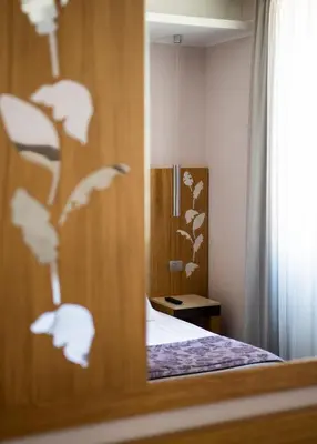 a reflection of a bedroom with a bed in a mirror at Hotel Giolli Nazionale in Rome