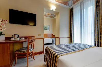 a hotel room with a bed and a desk with a chair at Hotel Amalfi in Rome