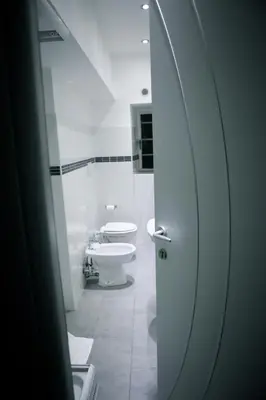 a white bathroom with two toilets and a sink at Arts & Rooms in Rome