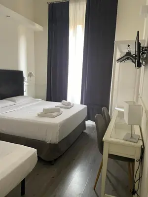 a bedroom with two beds and a table and a window at Arts & Rooms in Rome