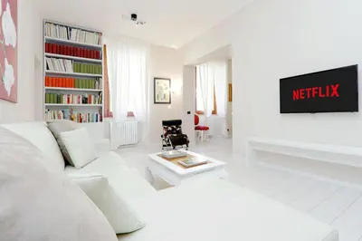 a white living room with a white couch and a tv at RomeAsYouLike-Colosseo Experience45 in Rome