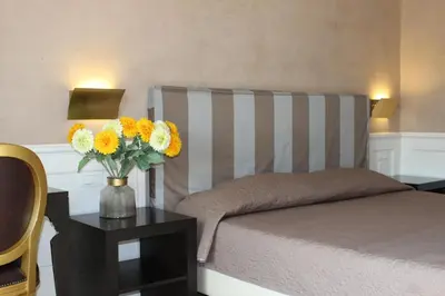 a bedroom with a bed and a vase of flowers on a table at Relais La Maison De Luxe in Rome