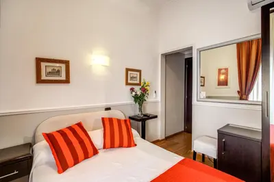 a bedroom with a bed with orange and white pillows at Hotel Everest Inn Rome in Rome
