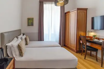 a hotel room with two beds and a desk at Relais Rione Ponte in Rome