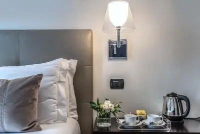 a bed with a table with two cups and a lamp at Relais Rione Ponte in Rome