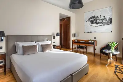 a bedroom with a large white bed and a desk at Relais Rione Ponte in Rome