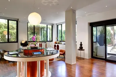 a living room with a table and chairs and windows at Hotel Pulitzer in Rome