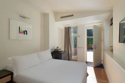 a white bedroom with a large white bed and a door at Hotel Principe Torlonia in Rome