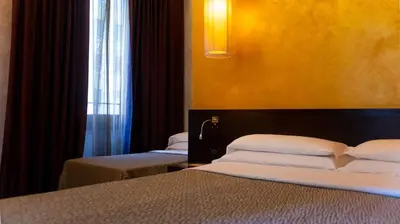 a hotel room with two beds and a window at Hotel Re Di Roma in Rome