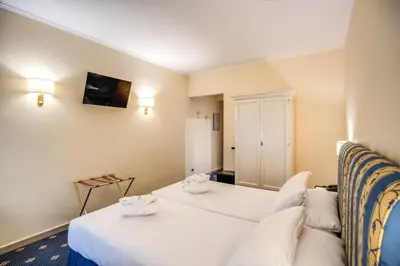 a hotel room with two beds and a couch at Hotel Napoleon in Rome