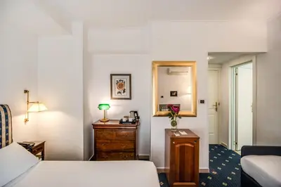 a bedroom with a bed and a dresser and a mirror at Hotel Napoleon in Rome