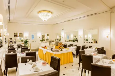 a restaurant with white tables and chairs and a chandelier at Hotel Modigliani in Rome