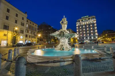 a fountain in the middle of a city at night at Hotel Modigliani in Rome