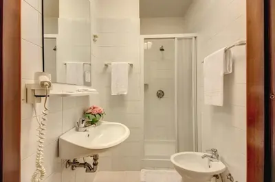 a white bathroom with a sink and a shower at Hotel Corona in Rome