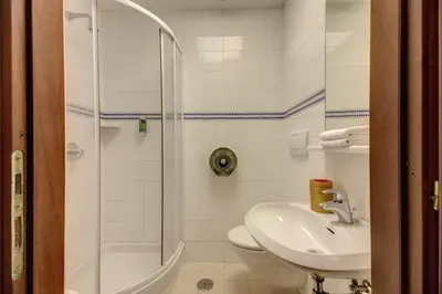 a bathroom with a shower and a toilet and a sink at Hotel Corona in Rome