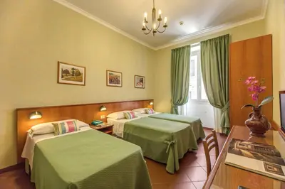 a hotel room with two beds with green sheets at Hotel Corona in Rome