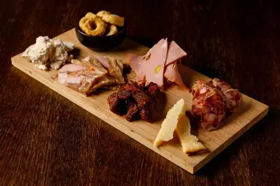 a wooden plate with meat and cheese on a table at Hotel San Francesco in Rome
