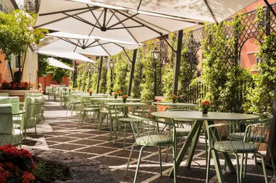 an outdoor patio with tables and chairs and umbrellas at Hotel Degli Aranci in Rome