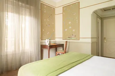 a bedroom with a bed and a desk and a window at Hotel Degli Aranci in Rome