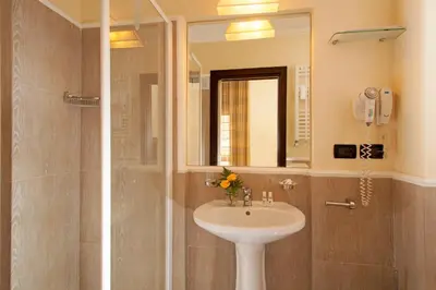 a bathroom with a sink and a shower with a mirror at Hotel Buenos Aires in Rome