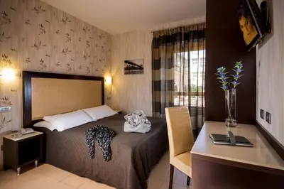 a bedroom with a bed and a desk with a laptop at Hotel Dei Mille in Rome