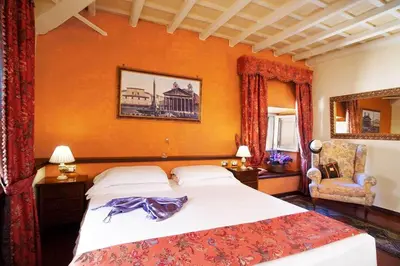 a bedroom with a large bed and a chair at Pantheon Inn in Rome