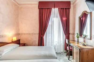 a bedroom with a bed and a desk and a window at Hotel Orazia in Rome