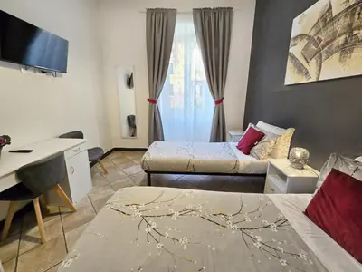 a room with two beds and a desk and a tv at Hosting Flats Hospety Group in Rome