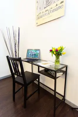 a desk with a laptop and a chair with a vase of flowers at Penelope Holiday in Rome