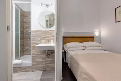 a bedroom with a bed and a bathroom with a sink at Penelope Holiday in Rome