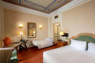 a hotel room with a bed and a desk and a mirror at Hotel Canada, BW Premier Collection in Rome