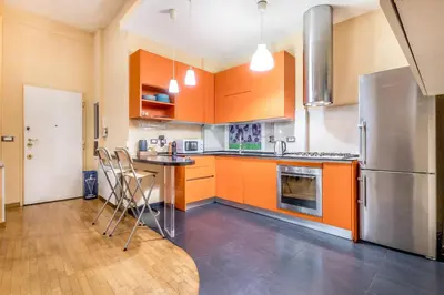 a kitchen with orange cabinets and a stainless steel refrigerator at Il gazebo a Monteverde in Rome