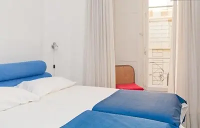 a bedroom with a blue and white bed and a red chair at 2 Be Home Colosseo in Rome