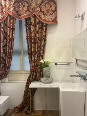 a bathroom with a window and a vase of flowers on a table at D.R.Rome Spanish Luxury Suites in Rome