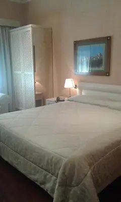 a large white bed in a room with a lamp at Colosseo Studio Suite in Rome
